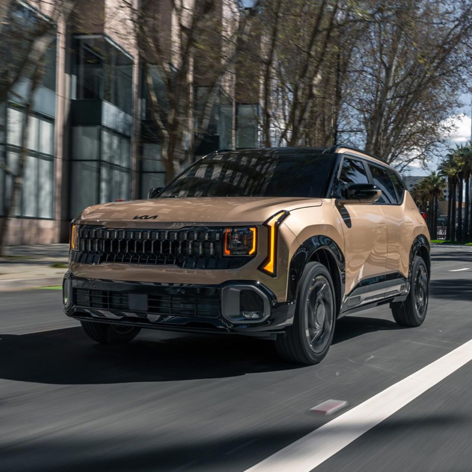 Low front angle shot of the 2027 Kia Seltos X-Line SX trim with all-wheel drive, cruising around a soft curve in the road in an urban environment.