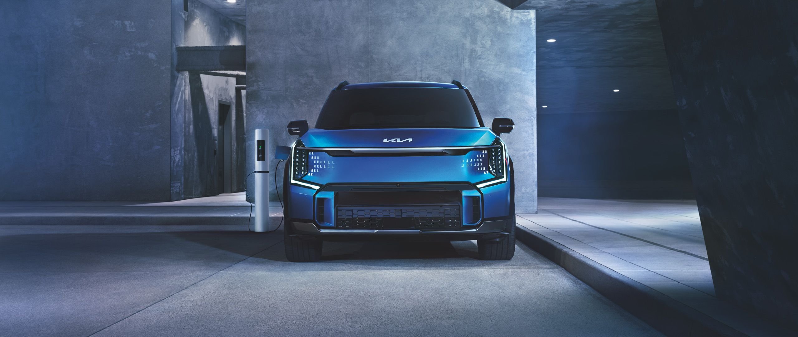 2024 Kia EV9 Wind in Ocean Blue Gloss charging in parking garage. 