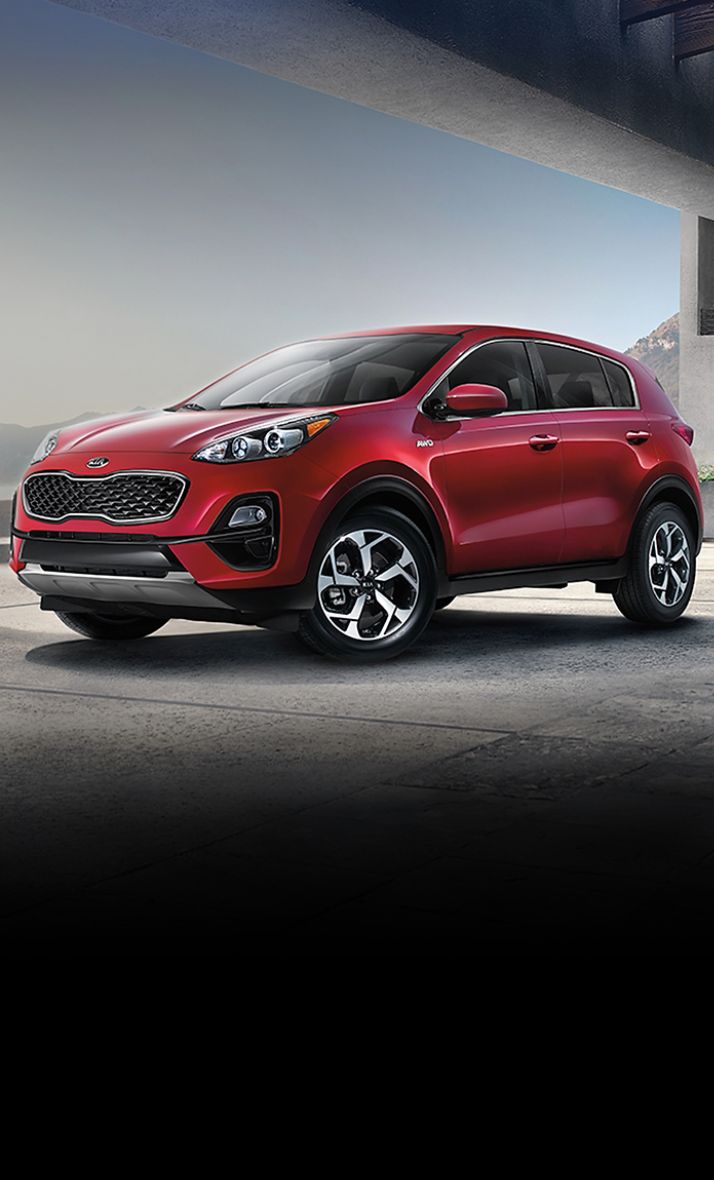 2022 Kia Sportage Parked In Front Of Mountains And A Lake Three-Quarter View
