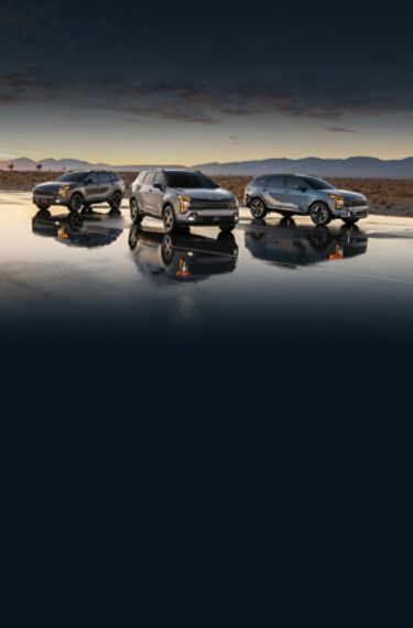 2026 Kia Sportage, Sportage Hybrid, and Sportage Plug-in Hybrid parked on wet pavement in the desert