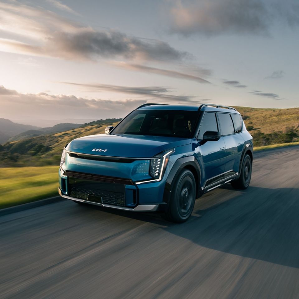 Blue Kia EV9 driving on a road