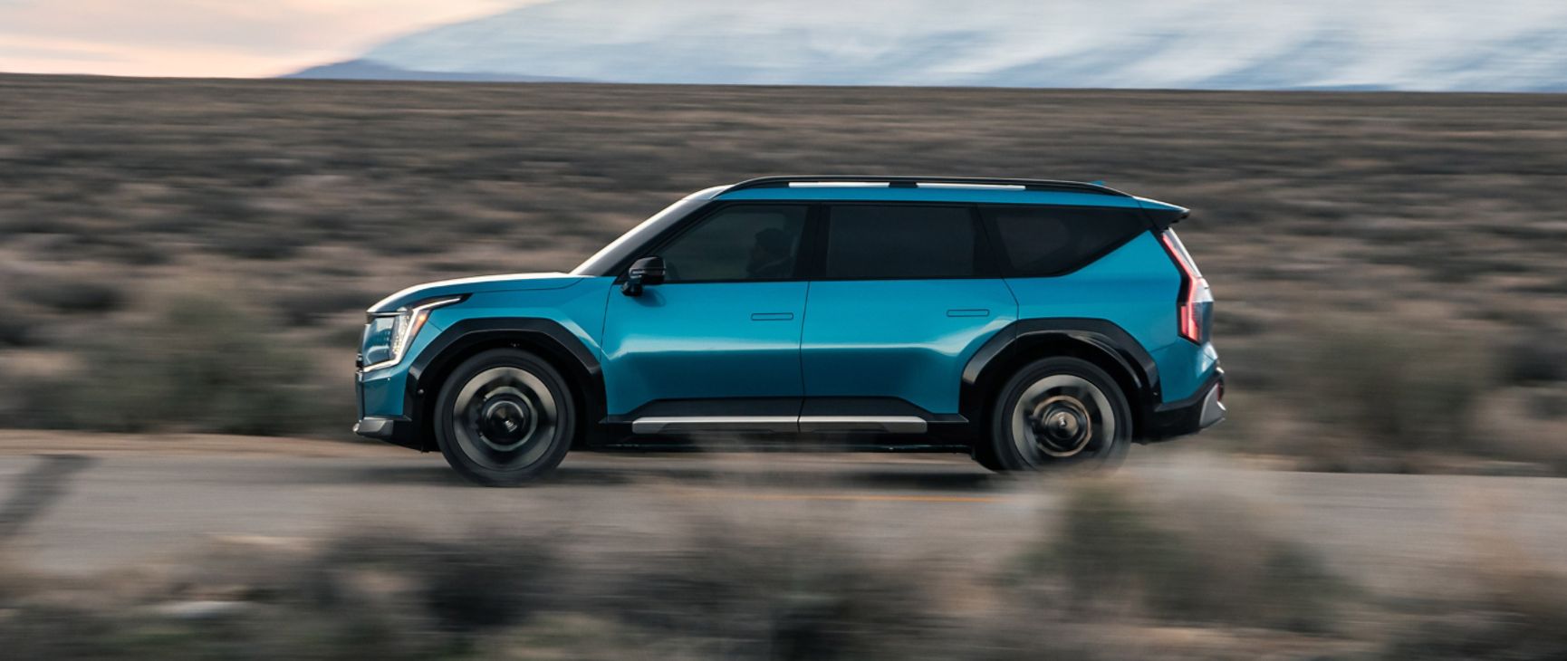 Side view of the blue Kia EV9 driving along the highway