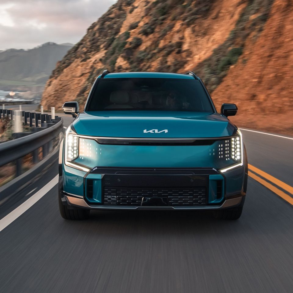 Front View of a blue 2026 Kia EV9 driving on the highway