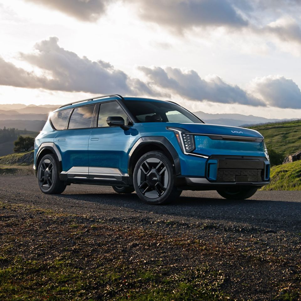 Side view of a blue 2026 Kia EV9 on a gravel road