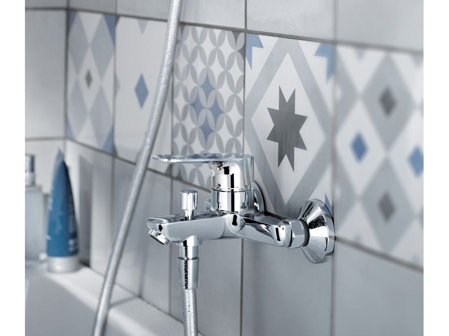 De la faïence en frise dans une salle de bains près d'une baignoire avec une robinetterie OSCAR