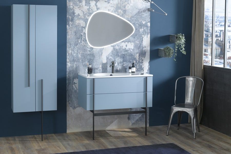 Une grande salle de bains avec des meubles bleus et un grand miroir asymétrique aux contours LED