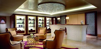Slide 16 of 20: A seating area, a reception desk and backlit shelves lined with spa products