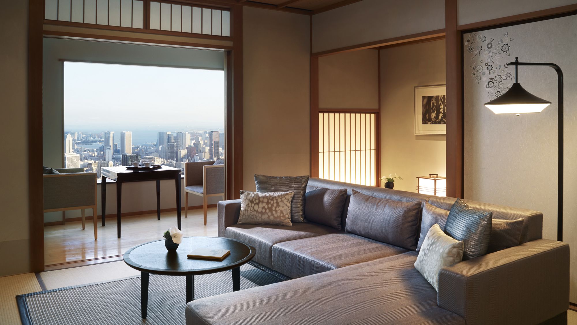 Modern living room with skyline views and features like a sleek, sectional sofa and Japanese-style walls