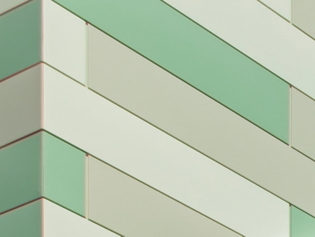 Close up of architectural building with green color-shifting geometric pattern.