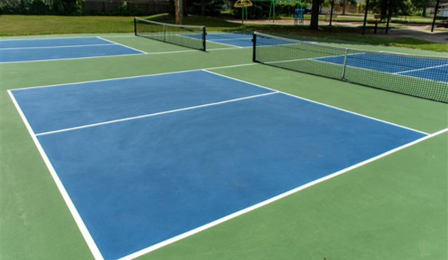 A sport court with blue and green surfaces, marked for tennis or similar activities