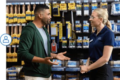 A paint pro talking to a Sherwin-Williams employee in front of a brush and roller display.