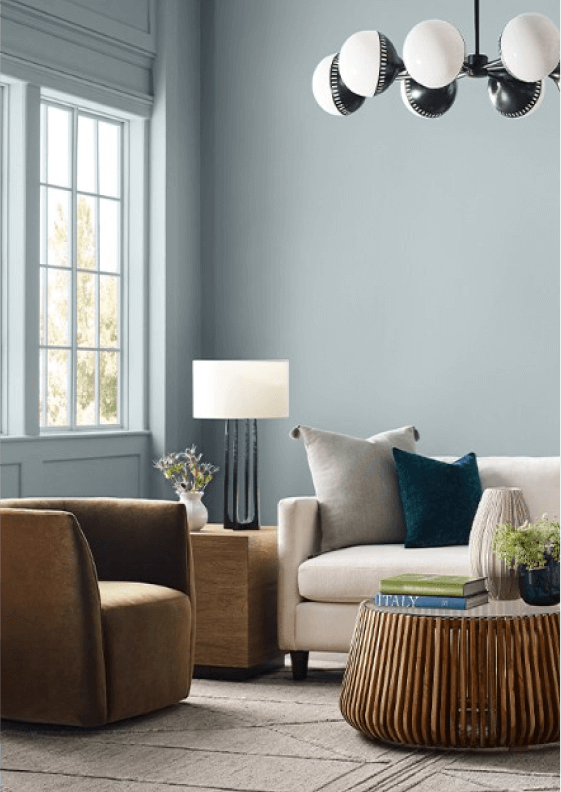 A sitting area with blue-gray walls set in front of a large window.