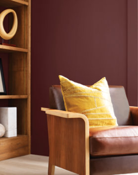 a wooden chair with cushions and a wooden book shelf behind it