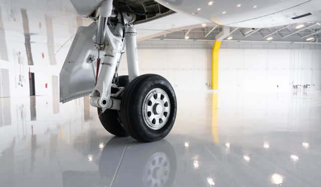 Airplane landing gear on resinous floor in hangar.