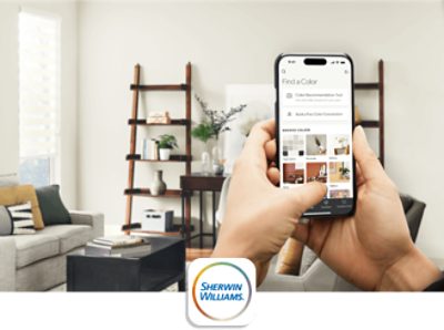 A person standing in their living room using an iPhone with the Sherwin-Williams Color Expert App to find a paint color.