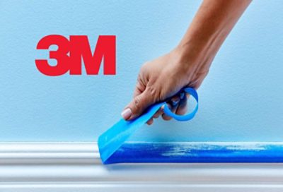 White baseboard with blue painters tape being peeled off by a hand, with 3M logo.