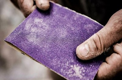 Hands holding 3M sandpaper.