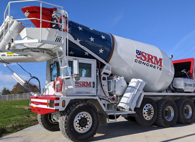 Full side view of a completed SRM Concrete front-discharge mixer truck with a glossy red, white and blue finish.