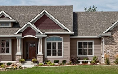 A suburban home with tan siding and a slanted roof.