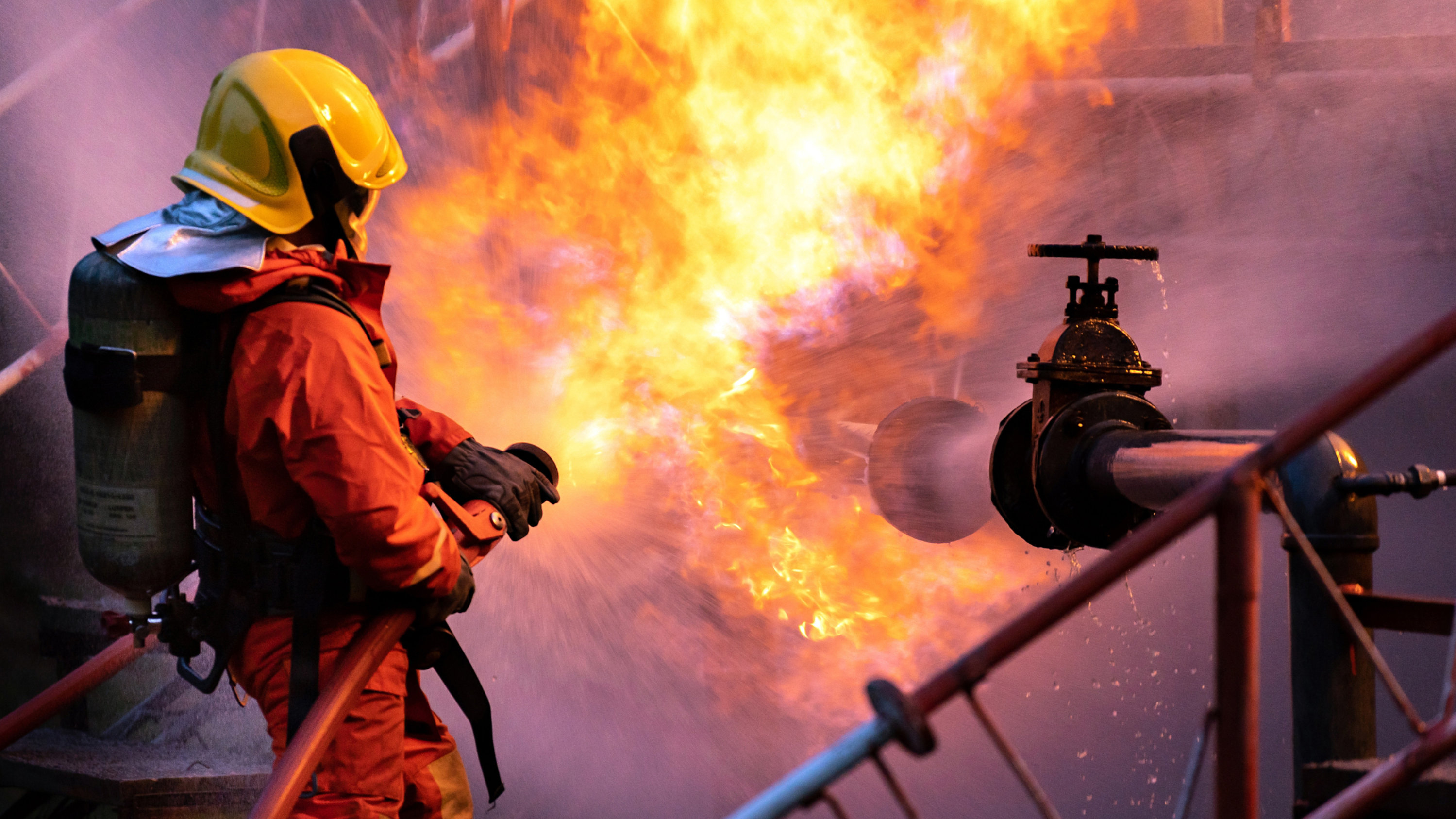 Firefighters using water fog spraying down fire from oil rig factory explosion