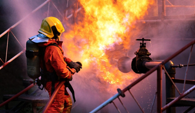 Firefighters using water fog spraying down fire from oil rig factory explosion