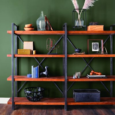 Wooden shelves with various items on them against a dark green wall.