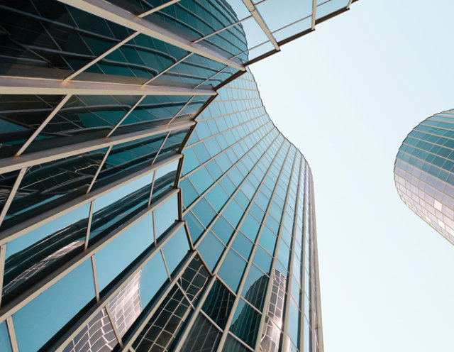 View from below of a monumental building featuring blue/black windows and extrusion coated with COTY 2026 Universal Khaki.
