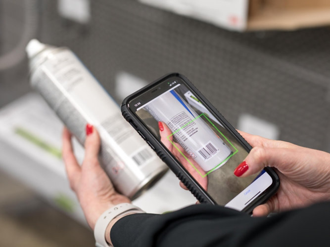 Phone in hand scanning bar code of an aerosol can