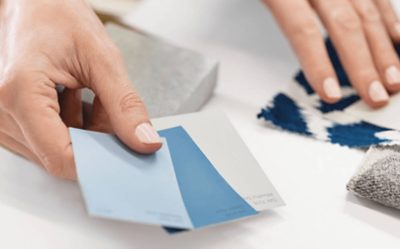 A woman's hands holding paint and fabric swatches.