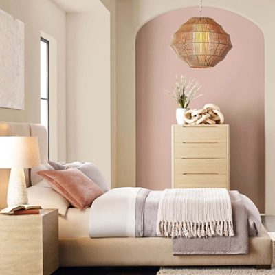 A bedroom with a light pink accent wall and light tan on the rest of the walls.