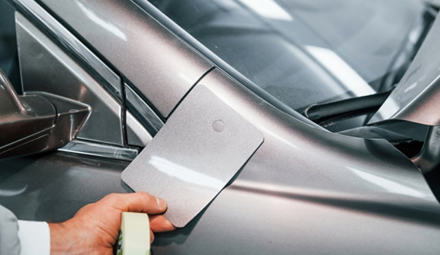 Person using a colour matching card against a silver car.