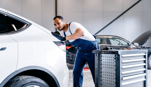 Automotive technician at auto service center, servicing a car.