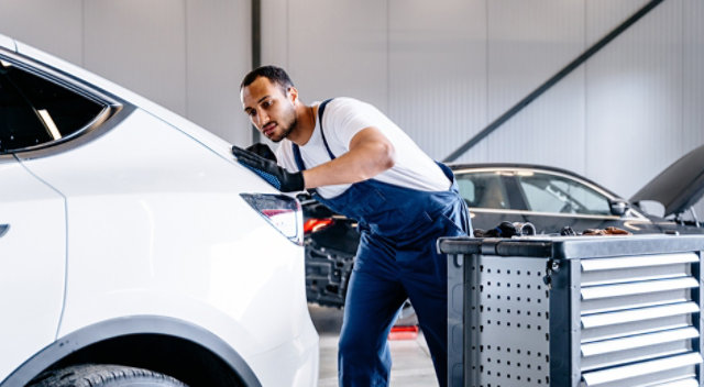 Automotive technician at auto service center, servicing a car.