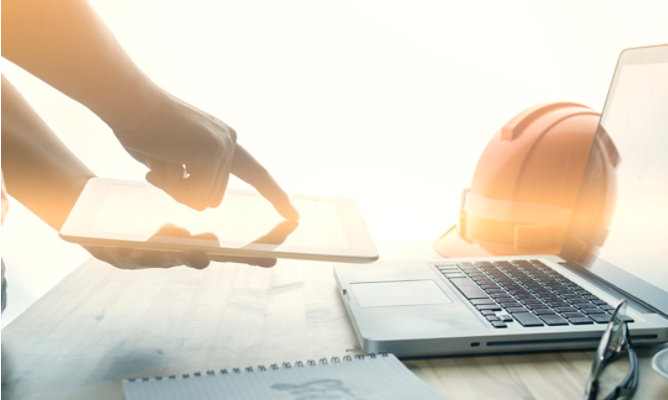 a person searching on a laptop with a hard hat on table