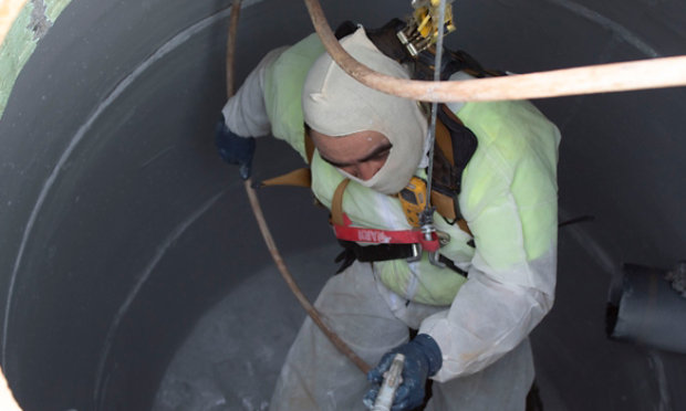 man in sewer applying coatings