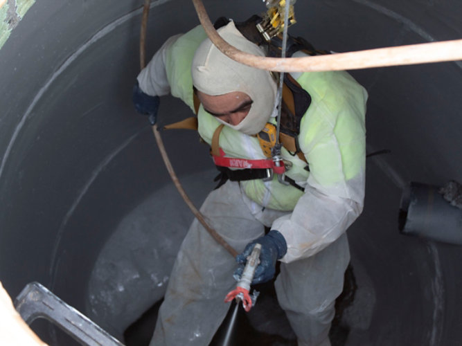 Contractor applying coatings in manhole