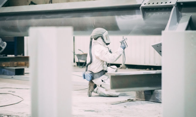 person applying fire protection on steel beam