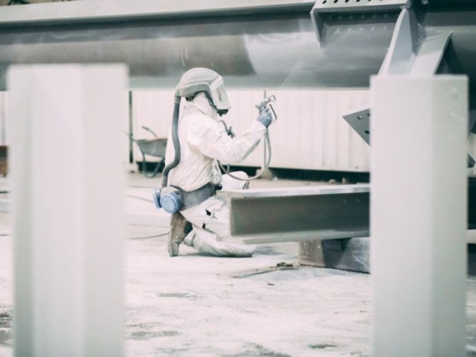 person applying fire protection on steel beam