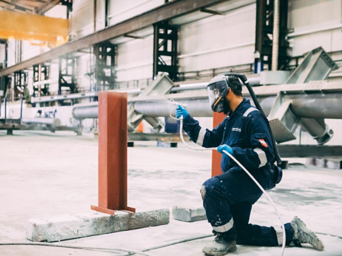 Applicator applying shop-applied fireproofing to a beam