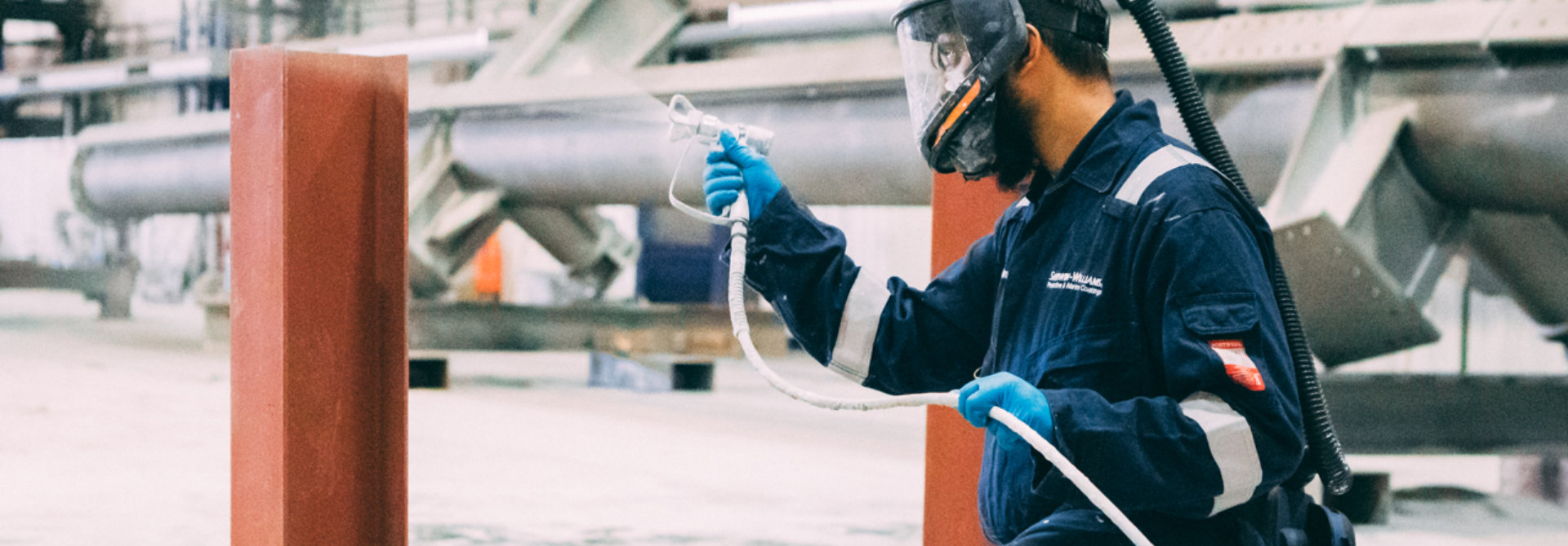 Person spraying fireproof coating on steel beam