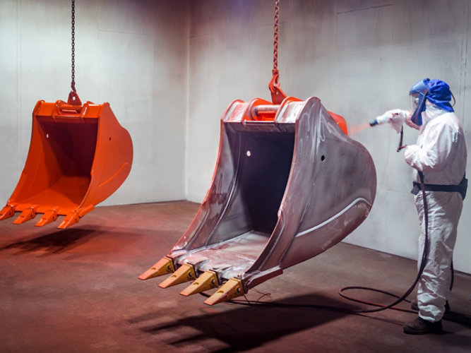 Protective coating being applied to heavy equipment buckets.