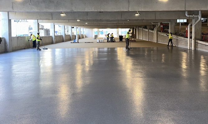 Partially finished floor with contractors working in the background.