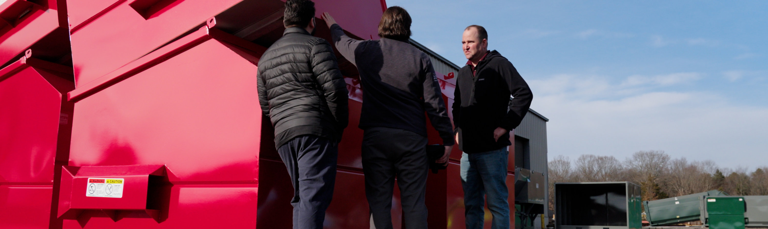 Inspecting large red industrial waste containers at a manufacturing facility