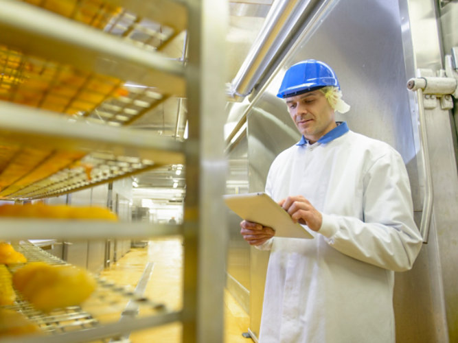 factory worker taking note of food prep