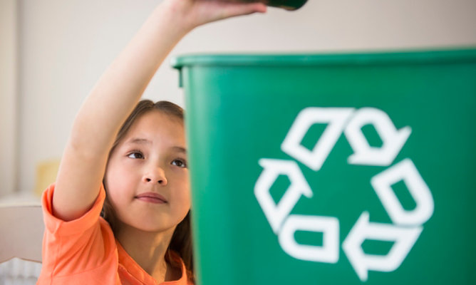 niño reciclando latas en un receptáculo