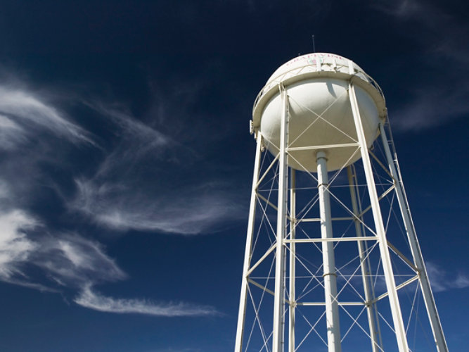 White legged water tower with dark blue sky and white clouds