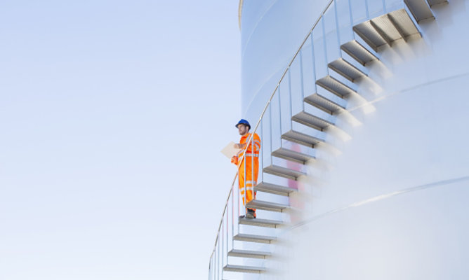 Man standing on stairs of an oil and gas tank