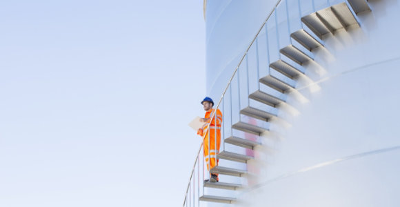 Man on the side of above ground oil and gas storage tank