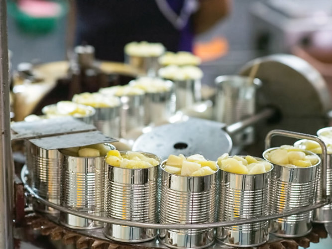 food cans filled with fruit on conveyor line