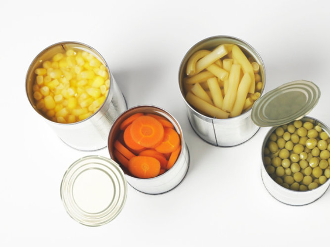 Latas de comida abiertas llenas de judías, maíz, zanahorias y guisantes.